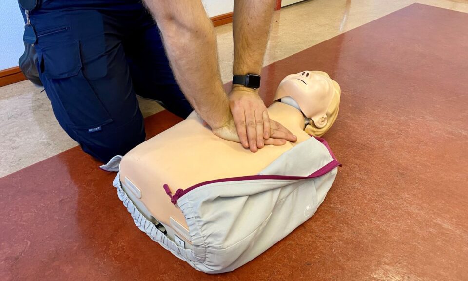 Två händer som visar hjärt- och lungräddning på en övningsdocka,